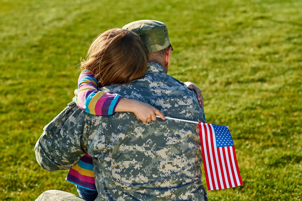 Military Service-member hugging his child good-bye before deploying. 